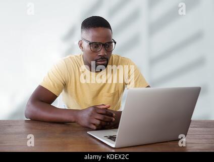 Digital composite of Businessman at desk with laptop with bright background Stock Photo