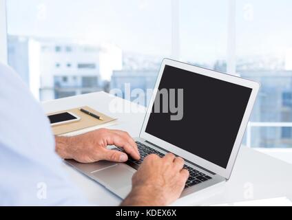 Digital composite of Businessman hands at desk with laptop with bright background Stock Photo