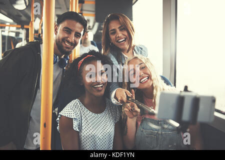 Diverse group of smiling young friends taking a selfie together while sitting on a bus Stock Photo