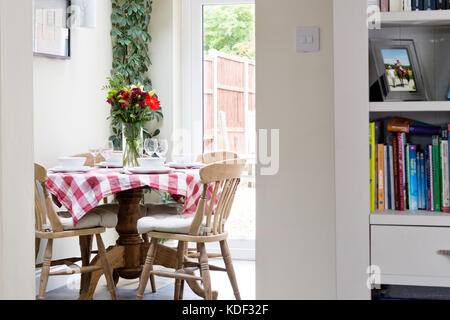 A small dining table with tablecloth set for lunch in a domestic dining room. Stock Photo