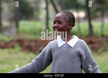 A young african girl in a school uniform smiles as she plays outside of her school in Njabini, Kenya Stock Photo