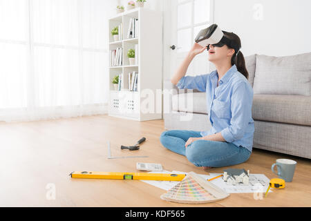 happy attractive women design new house interior plan and wearing virtual reality technology goggles looking 3D simulation blueprint drawing. Stock Photo