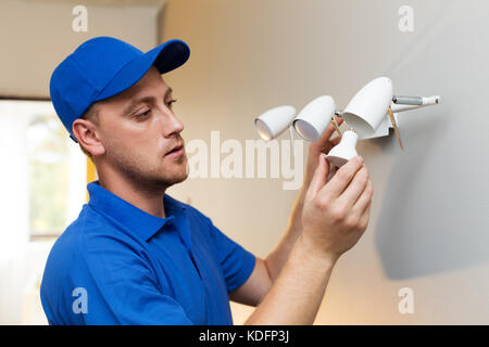electrical maintenance - electrician change light bulb in wall lamp Stock Photo