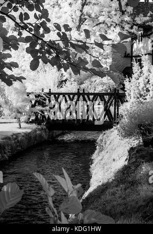 An infrared image of a footbridge over a millstream. Stock Photo