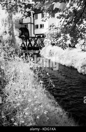 A small mill stream and mill wheel in Exmoor, Somerset shot in infrared. Stock Photo