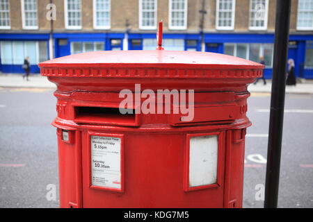 Red Royal Mail letter box in London, with blue offices in background Stock Photo