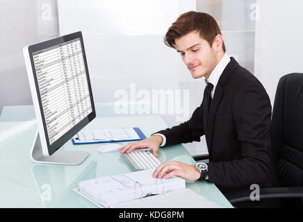 Portrait Of Young Businessman Using On Computer At Desk Stock Photo
