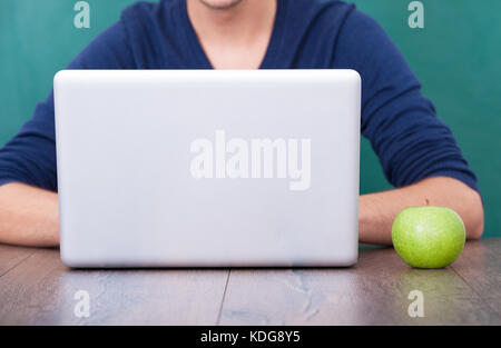 Man Using Laptop In Front Of Green Chalkboard Stock Photo