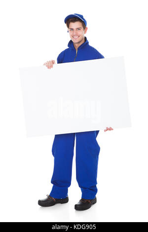 Portrait Of Male Worker Holding Blank Placard On White Background Stock Photo