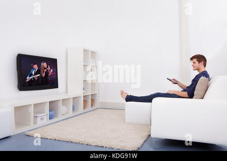 Young Man Sitting On Couch Watching Television Stock Photo