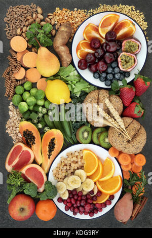 Healthy high fiber dietary food concept with fruit, vegetables, legumes, nuts, spice, cereals, whole wheat pasta and whole grain bread rolls on marble. Stock Photo