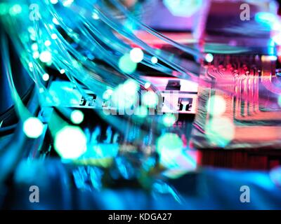 Fibre optic strands carrying data, with electronics of a laptop in the background. Stock Photo