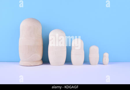 Wooden unpainted russian nested dolls -matryoshka- on blue background. Family concept. Stock Photo