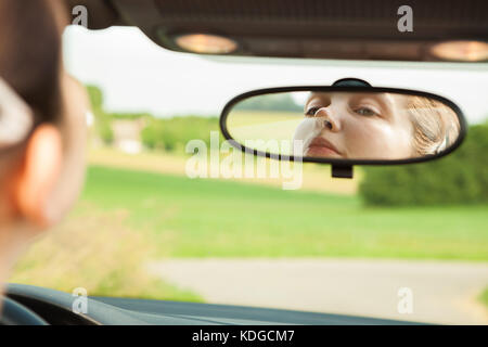 Young Woman Looking At Mirror While Driving The Car Stock Photo