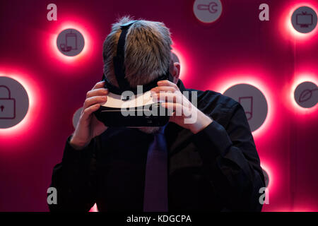 Young man trying out virtual reality glassess, holding with both hands on each side while he looks down Stock Photo