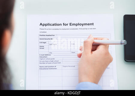 Close-up Of Woman's Hand Filling Application For Employment Stock Photo