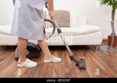 Young Maid Cleaning Floor With Handheld Vacuum Cleaner Stock Photo