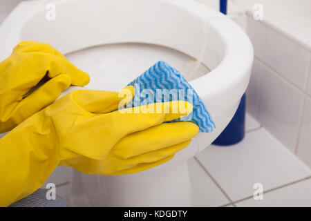 Close-up Of A Person's Hand Wearing Gloves Cleaning Toilet Stock Photo