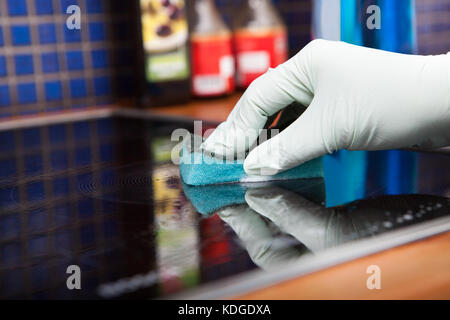Close-up Of Person's Hand Cleaning Induction Cooker With Scrubber Stock Photo