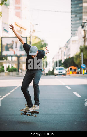 Pro skater riding skate, doing tricks and jumps on the main streets through cars and urban traffic. Free ride skateboard Stock Photo