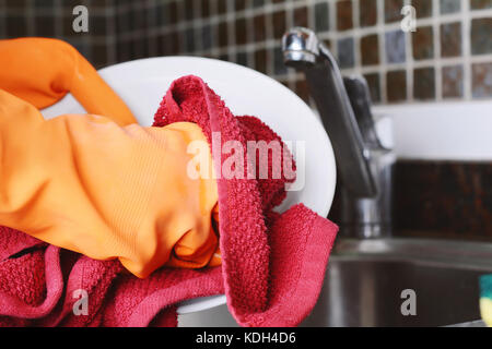 Close-up view of hands in rubber gloves washing dishes with sponge. Housework concept Stock Photo