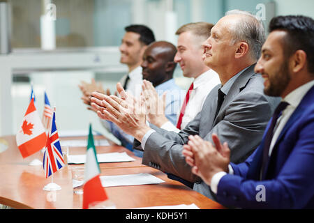 Row of delegates clapping their hands after successful speech of colleague Stock Photo