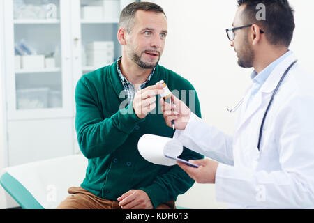Modern clinician giving bottle with pills to his patient during appointment Stock Photo