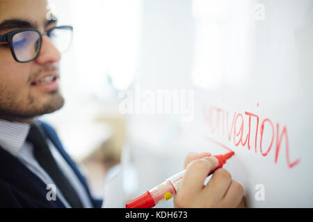 Businessman underlining word motivation written on whiteboard with red highlighter Stock Photo