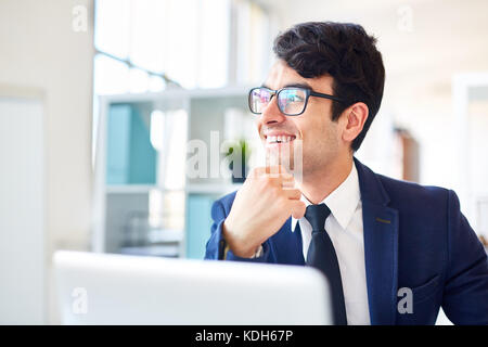Smiling young businessman looking aside while concentrating on thinking Stock Photo