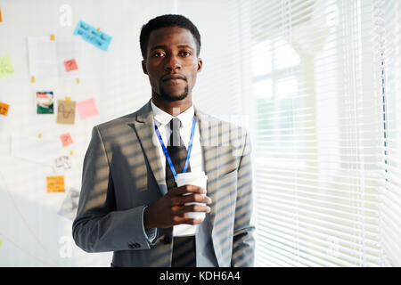 Confident young policeman in formalwear looking at camera on background of whiteboard with evidence Stock Photo