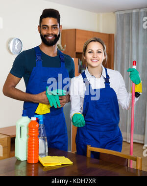 Positive black couple cleaning up together, vacuuming under carpet