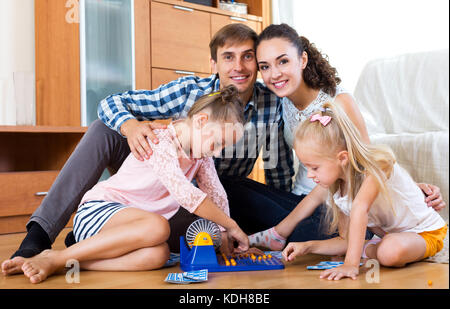 Positive little girls with parents trying chances at lotto game Stock Photo