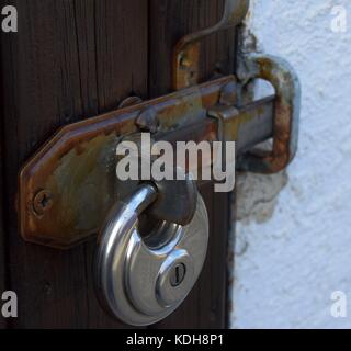 metal padlock on rusty door hinge with peeled paint Stock Photo