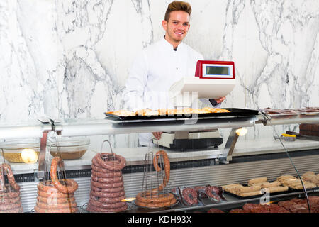 Happy seller in his grocery shop welcoming customers Stock Photo