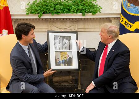 U.S. President Donald Trump is gifted a framed photo by Canadian Prime Minister Justin Trudeau during their Oval Office meeting at the White House October 11, 2017 in Washington, D.C. The photos show Trudeau’s father Prime Minister Pierre Trudeau meeting President Ronald Reagan in 1983, and a photo of President Trump and Prime Minister Trudeau meeting earlier this year. Stock Photo