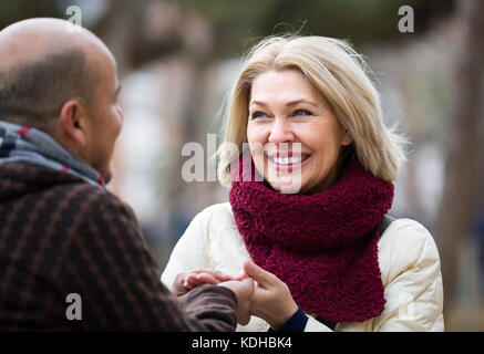Portrait of positive mature couple having interesting conversation outdoors Stock Photo