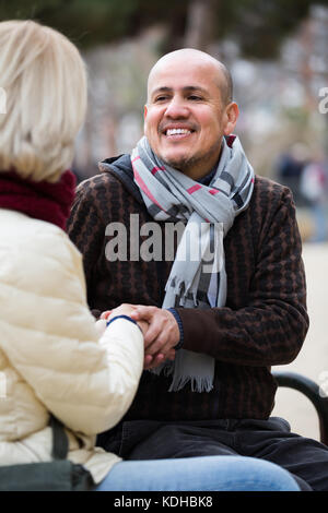 Portrait of cheerful smiling mature couple having interesting conversation outdoors Stock Photo