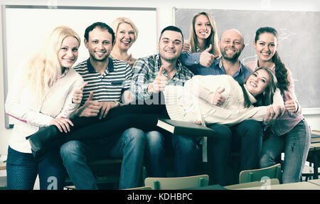 Happy female professor and cheerful students posing in classroom at extension courses Stock Photo