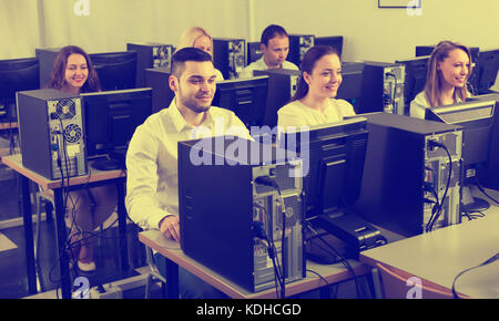 Working team sitting at desks in office and working at PC. Focus on man Stock Photo