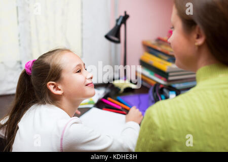 Young mother and daughter doing homework at home smiling happy doing ok ...