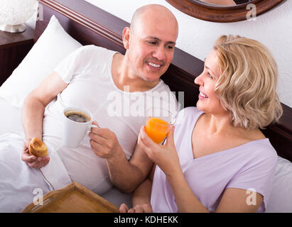 Happy smiling mature spouses having healthy breakfast in bed in the morning Stock Photo