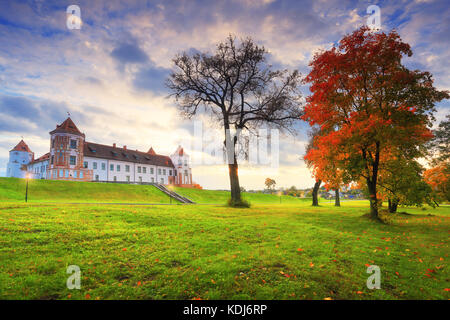 Autumn scene. Mir castle complex in autumn evening. Beautiful autumn park with maple. Stock Photo