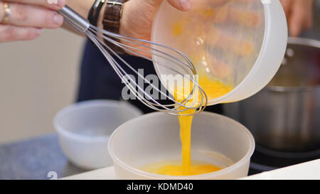 whipped egg yolks with sugar in a glass bowl. Beaten egg yolks in a bowl with whisk. Beaten egg yolk Stock Photo