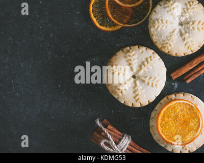 Top view of mince pies, baked crumbly pastry packed with fruits, tangy peel and spices. Concept of Christmas baking. Copy space. Stock Photo