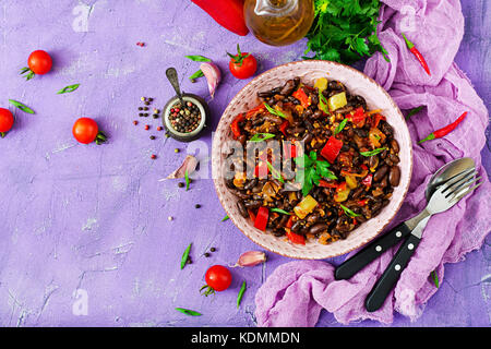 Stewed black beans with sweet peppers and tomatoes with spicy sauce in a pink bowl Stock Photo