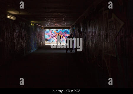 People walking through a tunnel with heavy graffitti in Prague, Europe