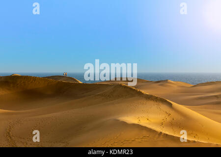 Unrecognizable couple walking throiugh the dunes of Maspalomas in the evening Stock Photo