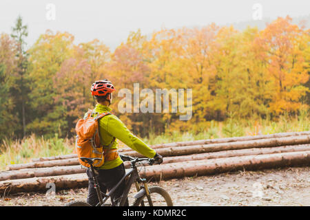 Mountain biker looking at inspiring mountain landscape, standing with bicycle. Man cycling MTB on dirty road in woods. Sport and active recreation, fi Stock Photo