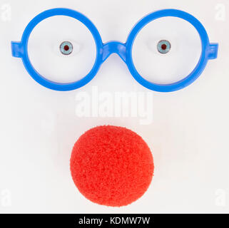 Simple blue plastic glasses frames, doll eyes and red foam clown nose. Stock Photo