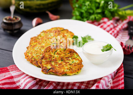 Zucchini pancakes with parsley on a wooden table. Stock Photo